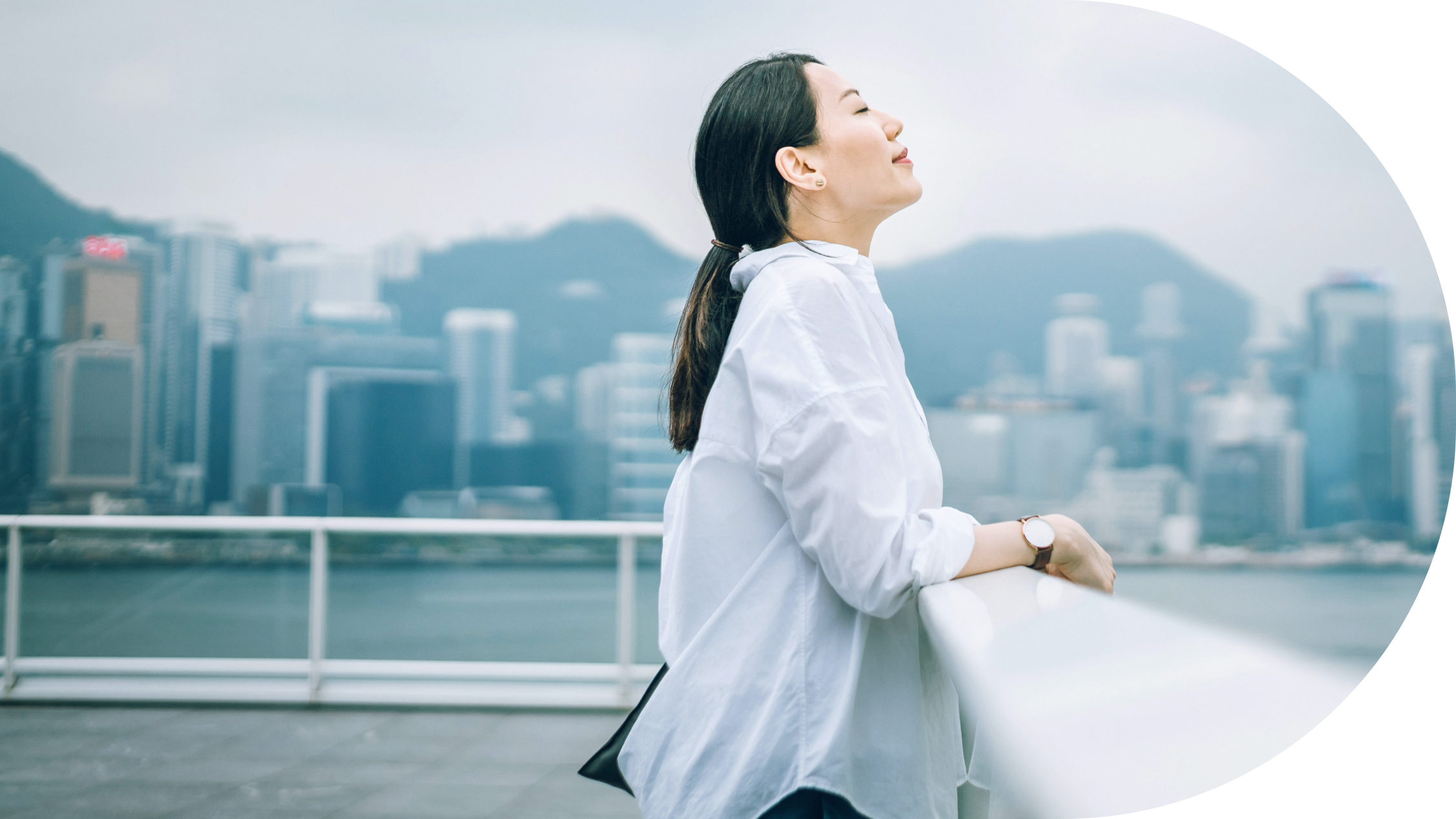 Woman looking over water with face to the sky