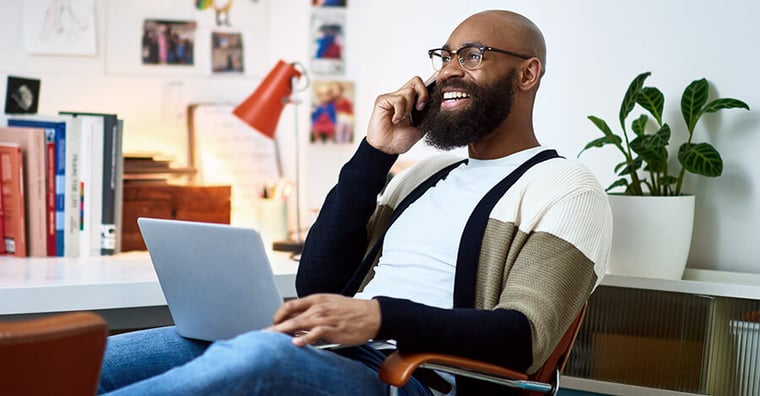 man talking on phone while on the computer