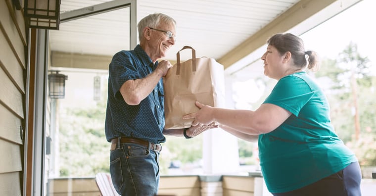 Volunteer delivering food to elderly person at home