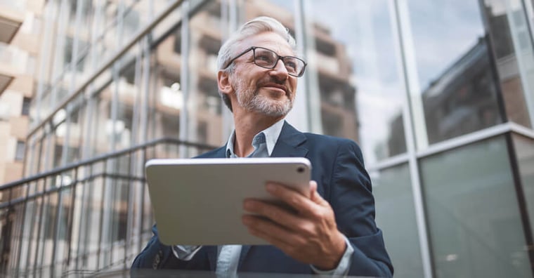 executive male looking at tablet standing outside of hospital 
