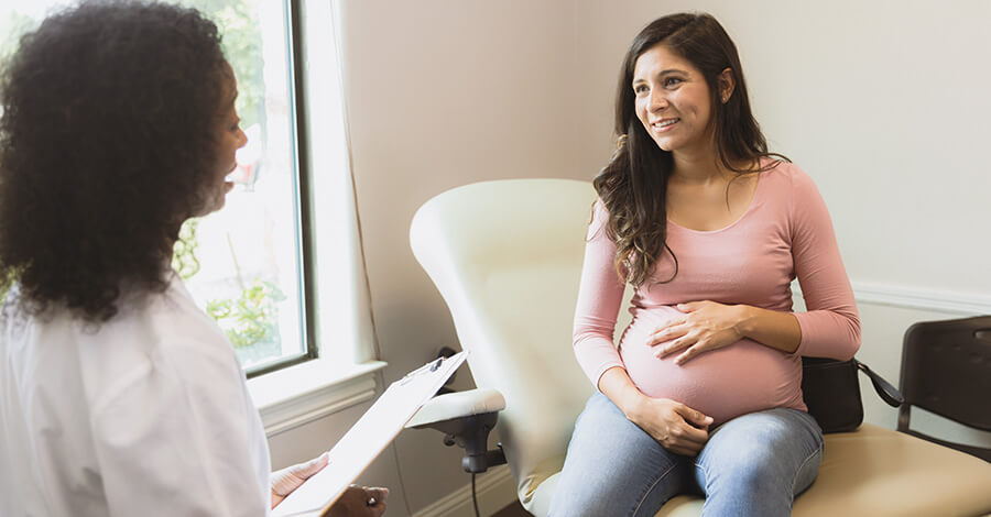 happy pregnant woman talking with her doctor