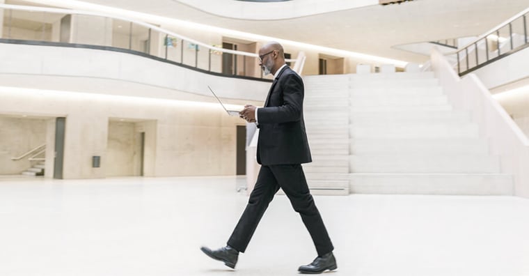 hospital executive walking and looking at laptop