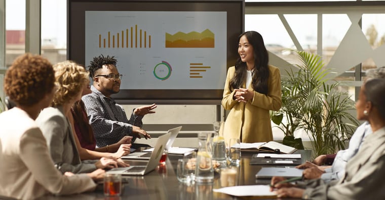 professional woman presenting metrics to team of colleagues
