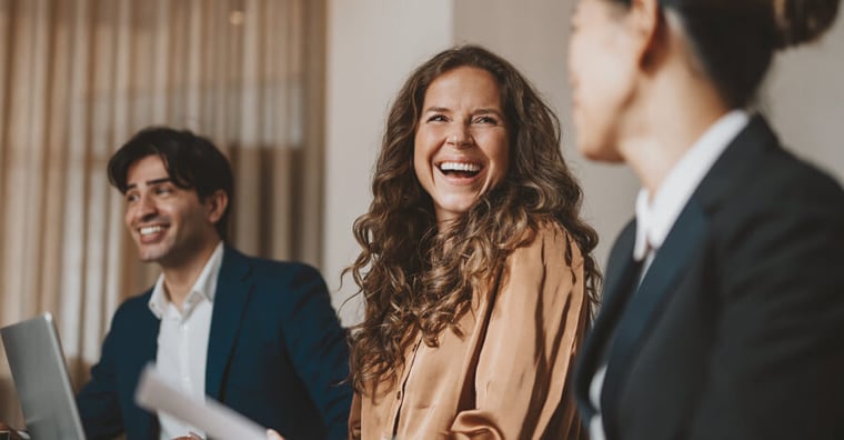 female colleagues smiling at each other and holding paperwork