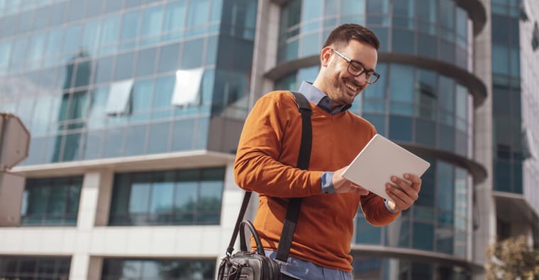 smiling man on tablet in street