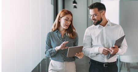 Two business professionals talking and reviewing a tablet
