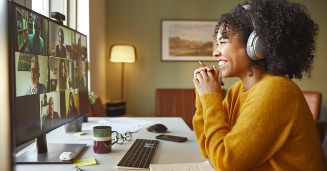 woman smiling while attending a virtual meeting that's shown on her computer screen